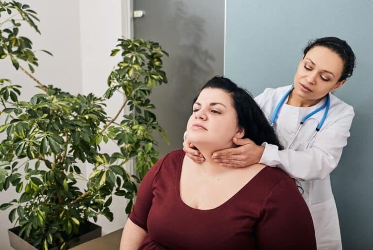 Surgeon palpates woman patient's neck