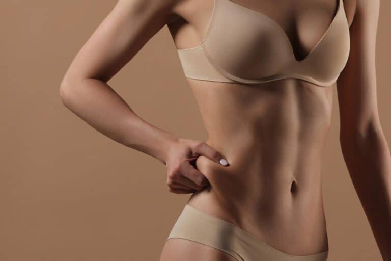 woman holding abdomen fat in underwear candidate for liposuction or liposculture