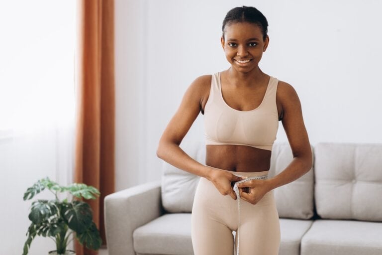 young black woman measuring waist wearing compression garment