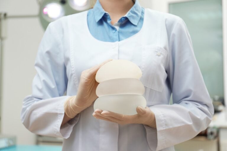 surgeon holding pile of breast implants