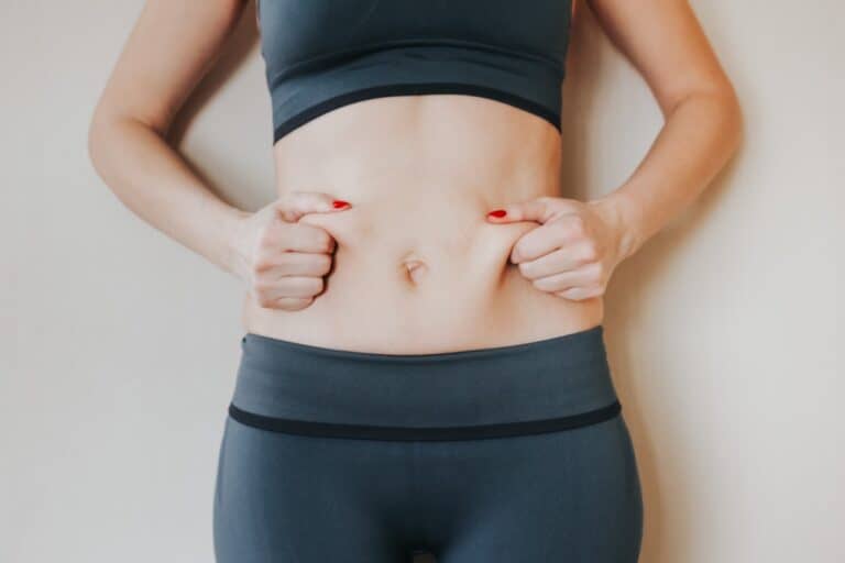 slim woman pinching her belly skin
